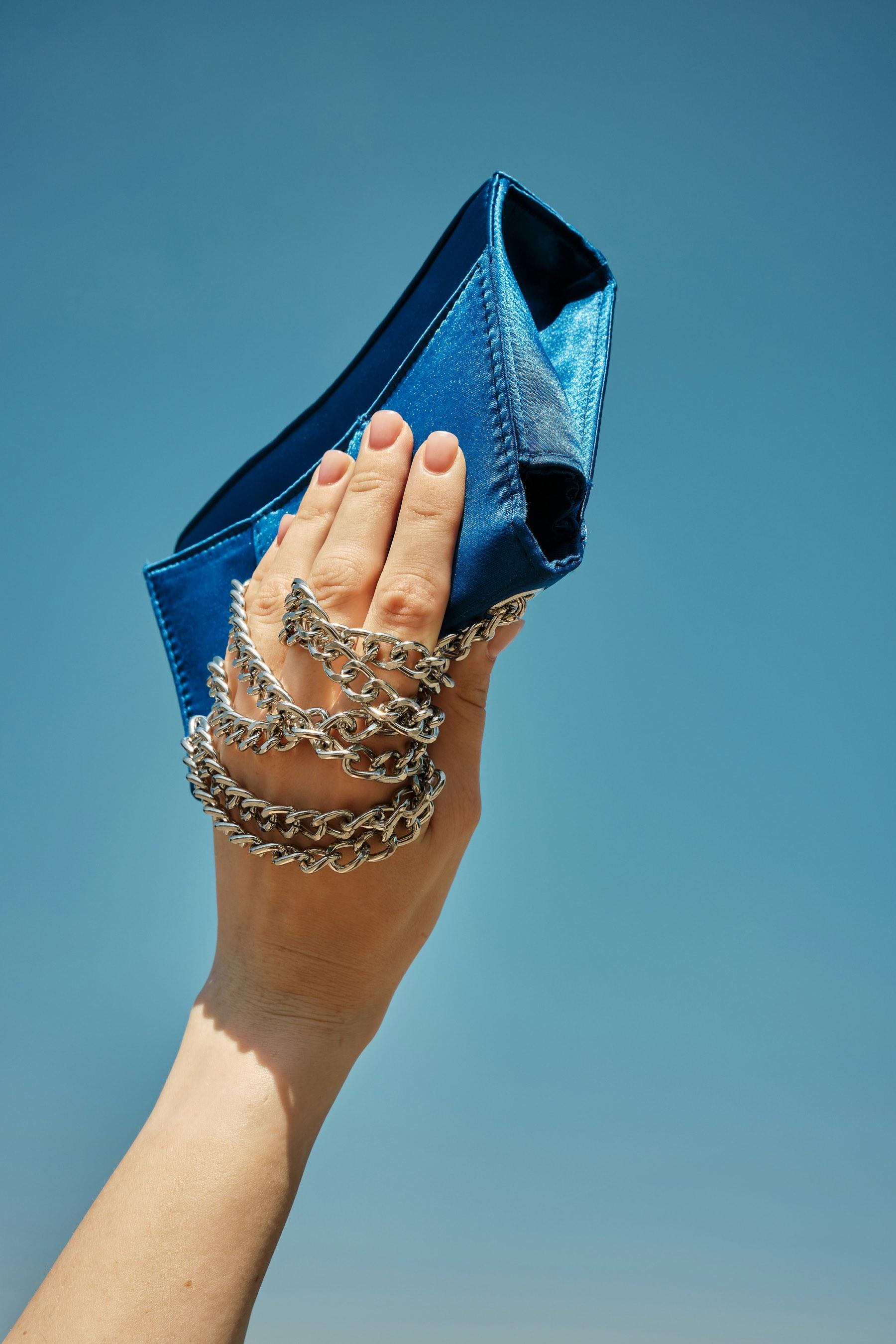 A blue satin clutch against the sky