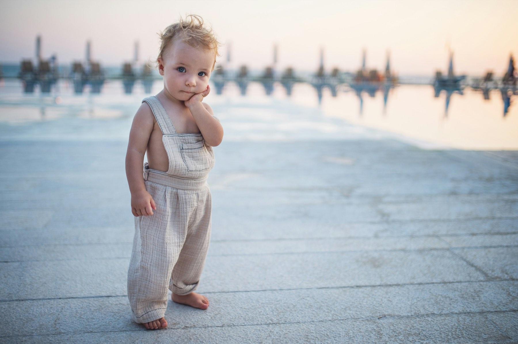 A toddler in linen dungarees